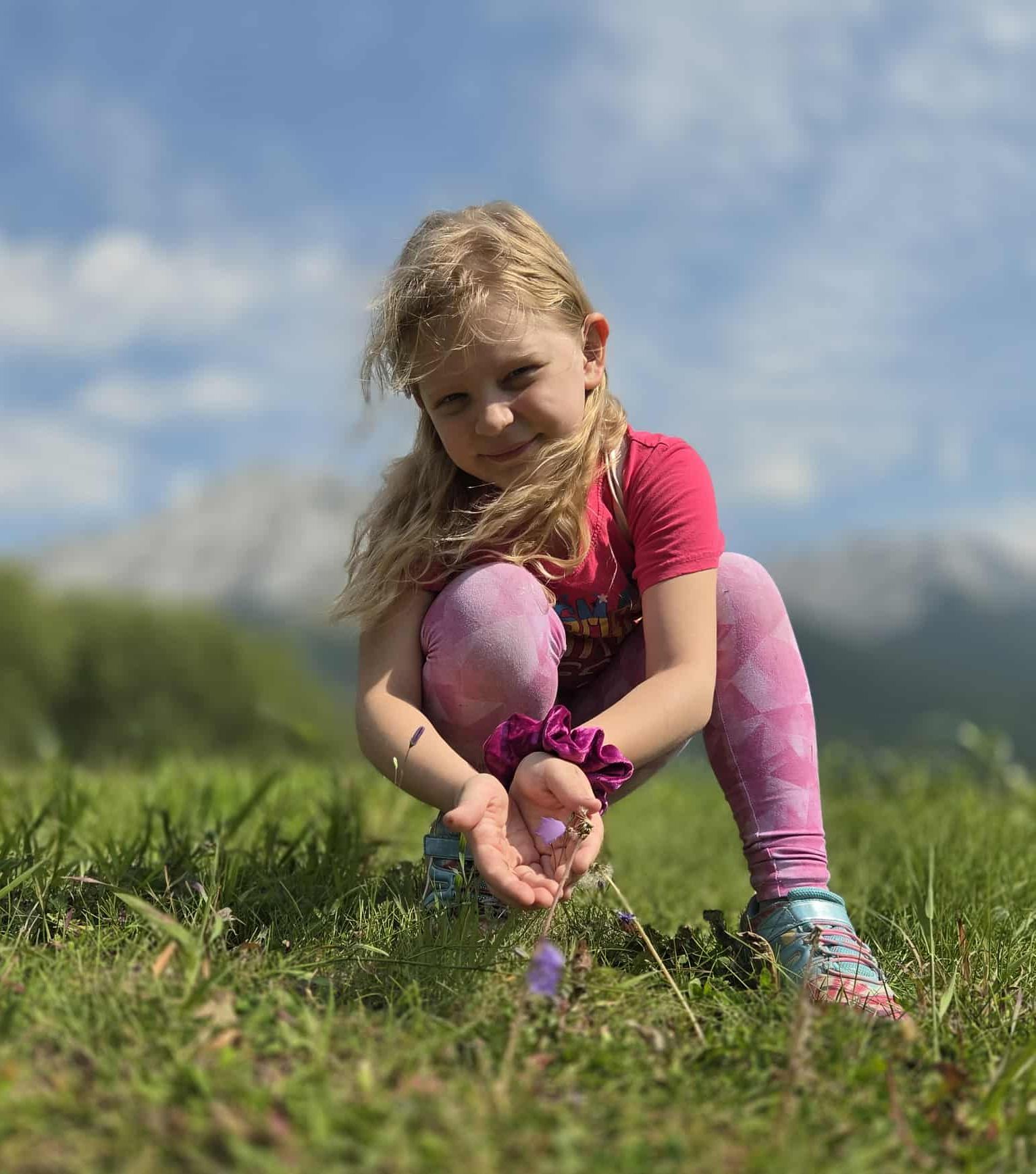 A girl in pink t-shirt holding a flower