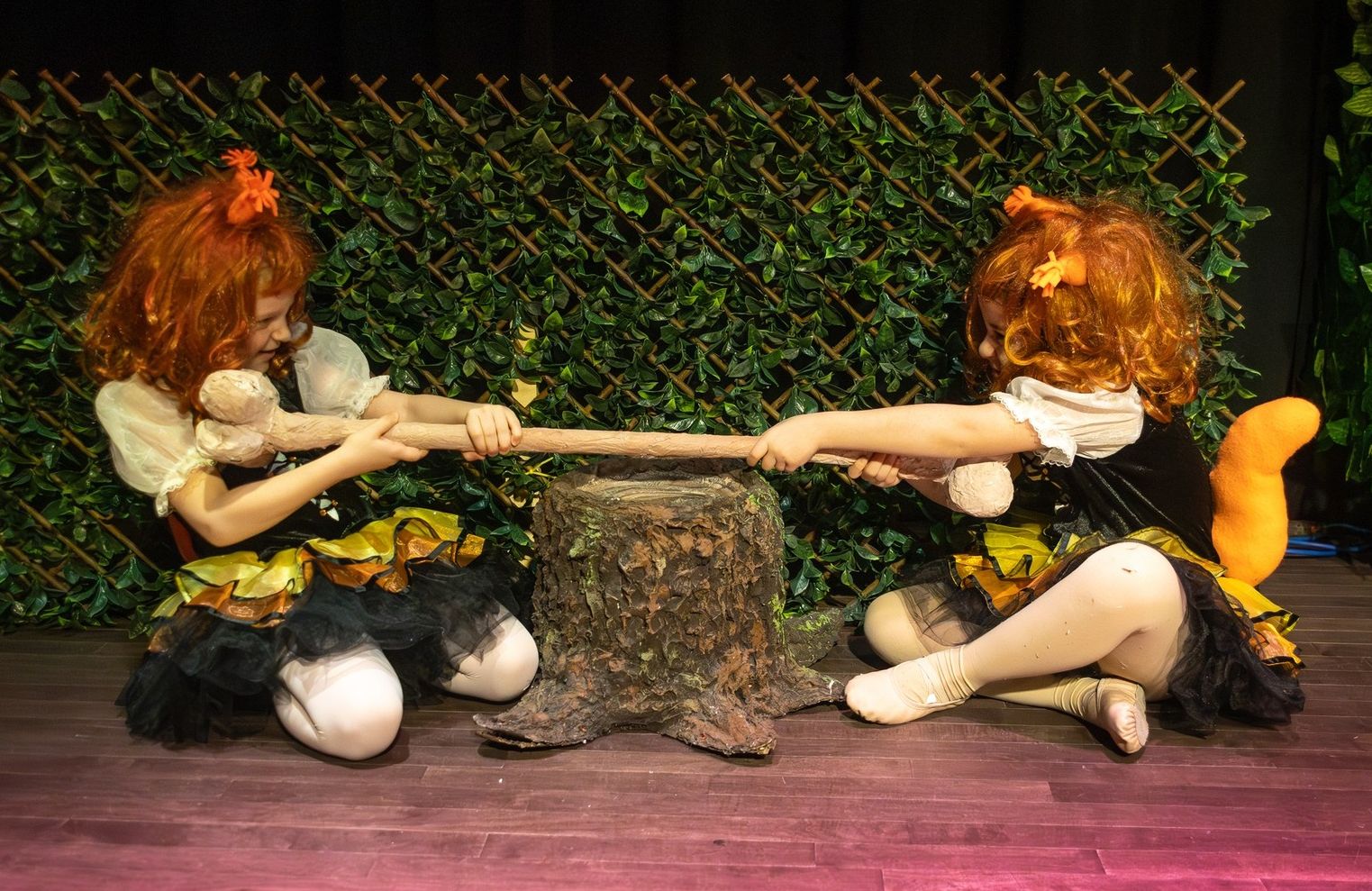 Two girls pulling a bone while performing on stage